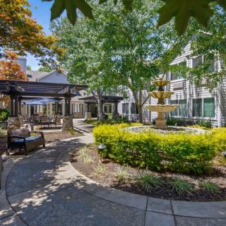 A beautifully landscaped courtyard with a fountain, surrounded by trees and seating areas.
