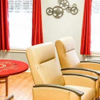 A cozy living room setup with beige chairs, red curtains, and decorative wall art.