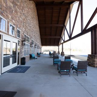 A spacious outdoor patio with seating and a stone wall under a large veranda.
