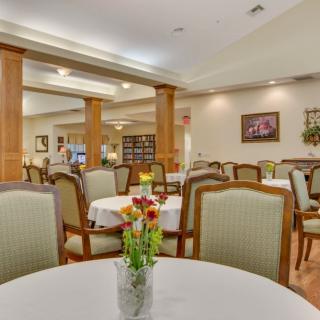An elegant dining room with tables set for a meal, featuring floral centerpieces and cozy lighting.