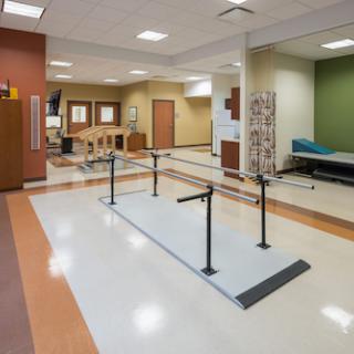 Inside view of a rehabilitation therapy room featuring walking bars for patient assistance.