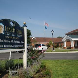 A nursing and rehabilitation center with a sign and flags in front of the building.