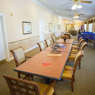 A well-lit conference room featuring a long table surrounded by chairs, with ceiling fans and wall decorations.