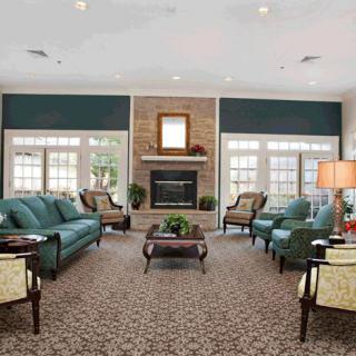 A modern living room with multiple seating arrangements, featuring a central fireplace and elegant furniture.