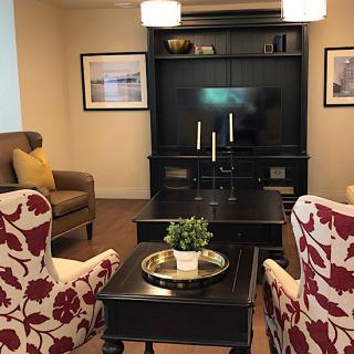 A cozy and modern living room with patterned armchairs, a central coffee table, and an entertainment unit with a television.