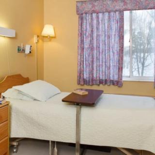 A simple hospital room with a bed and a window.