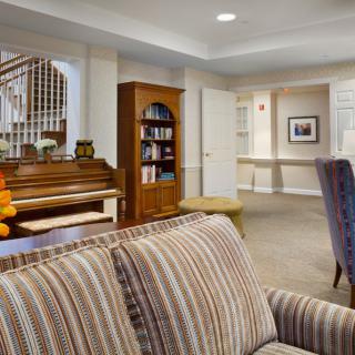 A cozy living room with a piano and a bookshelf as focal points.