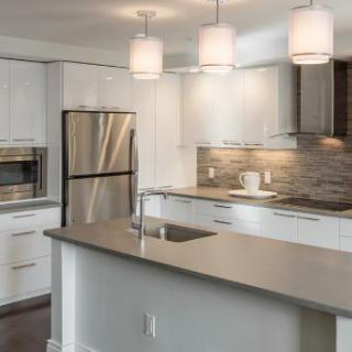 A modern kitchen featuring a sleek design with stainless steel appliances, a central island, and pendant lighting.
