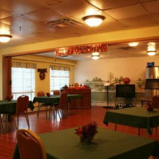 A cozy restaurant dining area with tables and chairs set up, featuring warm lighting and simple decor.