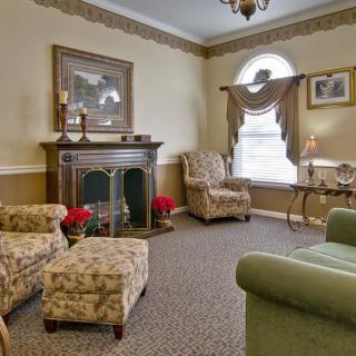 A cozy living room with classic decor, featuring armchairs, a fireplace, and elegant furnishings.