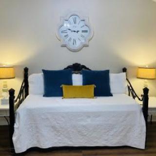 A cozy bed with decorative cushions and a stylish wall clock.