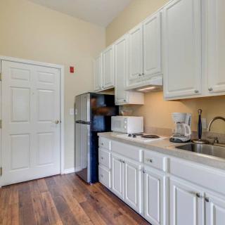 A modern kitchen with white cabinets, stainless steel appliances, and wooden flooring.