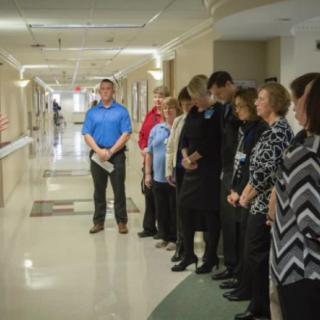 A group of people standing in a hallway, possibly during a meeting or event.