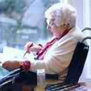 An elderly woman sitting in a wheelchair by a window.
