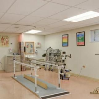 A rehabilitation therapy room equipped with parallel bars and various exercise machines.