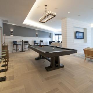 Modern recreational room featuring a pool table and bar seating.