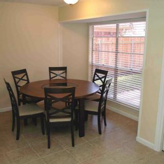 A cozy dining area with a round table and six chairs by the window.