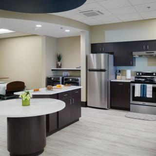 A contemporary kitchen featuring stainless steel appliances, a central island with a white countertop, and sleek dark wood cabinets.