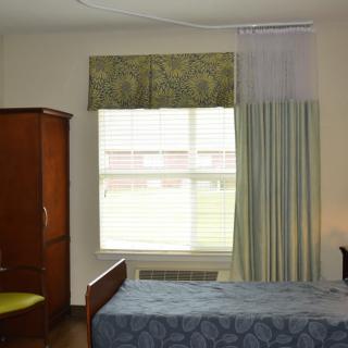 A minimalist bedroom with a bed, wardrobe, and a window with curtains.