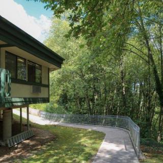 A house with a pathway leading into a lush forest area.