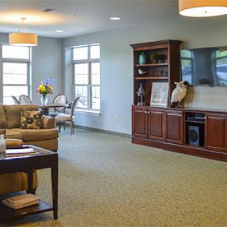 A cozy living room featuring comfortable seating, a television unit, and natural light filtering through large windows.
