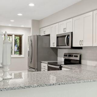A beautifully renovated modern kitchen featuring sleek white cabinets and granite countertops.