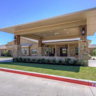 A modern building entrance with a stone facade and well-maintained landscaping.
