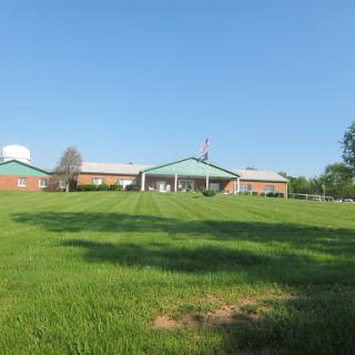 A serene view of a building set against a clear blue sky and lush green grass.