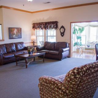 A cozy living room with leather sofas and a coffee table, featuring large windows and stylish decor.