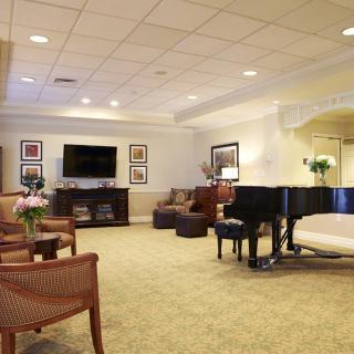 A spacious and elegantly designed living room with a grand piano, comfortable seating, and modern decor.