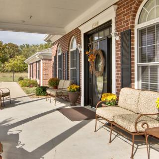 A welcoming porch with comfortable seating and seasonal decorations on a brick house.