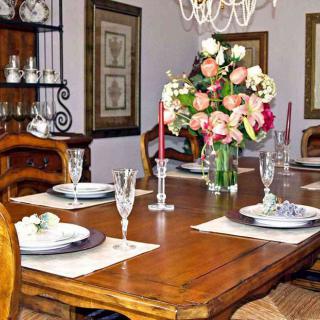 A beautifully set dining table with elegant dinnerware, floral centerpiece, and candles.