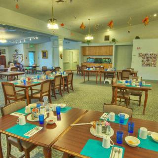 A spacious dining area with neatly arranged tables and chairs, featuring inviting place settings and warm lighting.