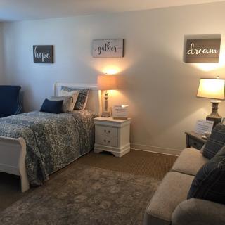 A cozy bedroom with a bed, sofa, and ambient lighting from lamps.