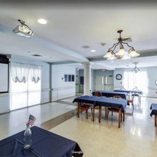 A spacious conference room with tables and chairs, equipped with a projector and elegant chandeliers.