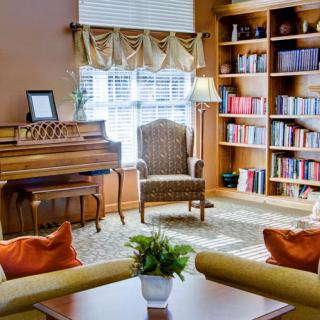 A cozy living room with a piano, bookshelves, and comfortable seating.