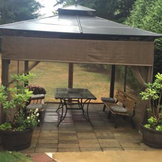 A cozy outdoor patio area with a gazebo and seating surrounded by plants.