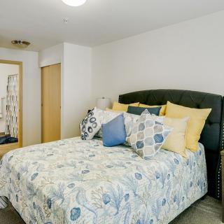 A cozy bedroom with a neatly made bed featuring patterned bedding and multiple decorative pillows.