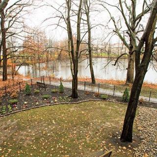 A serene autumn view of a park with bare trees and a calm lake in the background.