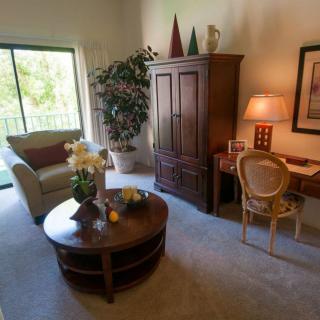 A cozy living room with an armchair, coffee table, desk, and lamp.