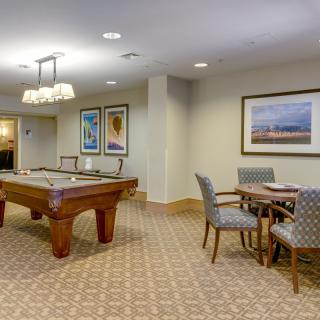 A well-lit game room featuring a pool table and seating area with artwork on the walls.