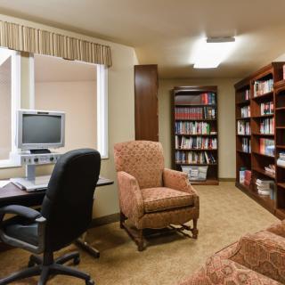 A cozy library corner with bookshelves, a computer desk, and comfortable seating.