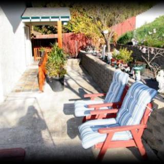 A sunny patio with two cushioned chairs and surrounding plants, ideal for relaxation.