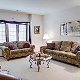 A cozy living room featuring two sofas, a glass coffee table, a lamp, and a large mirror.