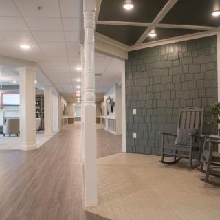 A modern lobby interior with a corridor, featuring a rocking chair and wooden flooring.
