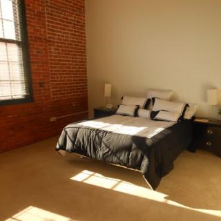 A minimalist bedroom with a brick wall, large window, and modern design elements.