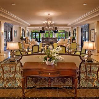 A luxurious and traditional hotel lobby with elegant furniture and a central chandelier.
