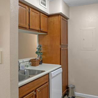 A compact kitchen area with wooden cabinets, a sink, and a dishwasher.