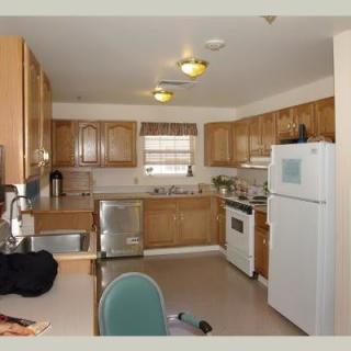 A cozy kitchen with wooden cabinets, featuring an oven, refrigerator, sink, and various appliances.