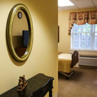 A cozy bedroom interior featuring a wall mirror, a bed, and a window with curtains.